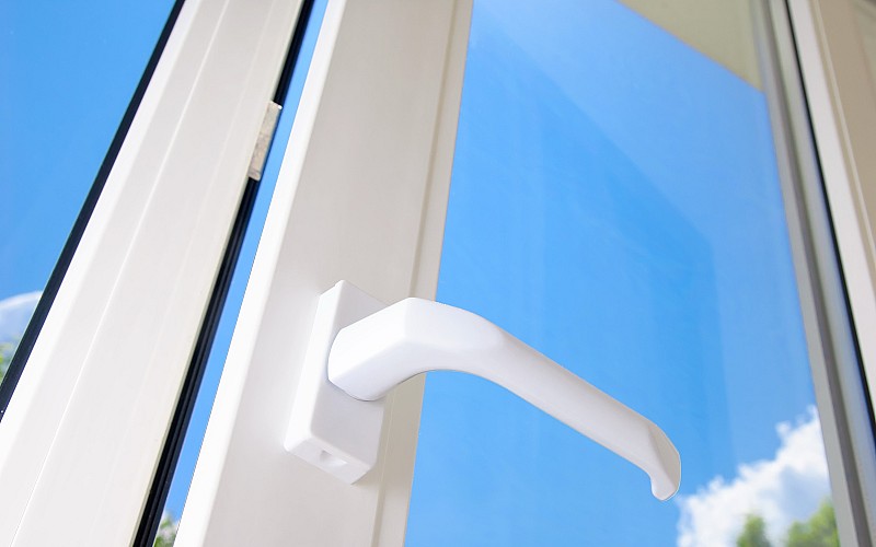 Nahaufnahme eines geöffneten weißen Kunststofffensters mit blauem Himmel im Hintergrund